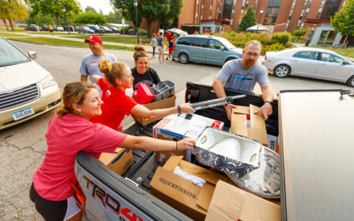 Student volunteers unloading a new student's vehicle.