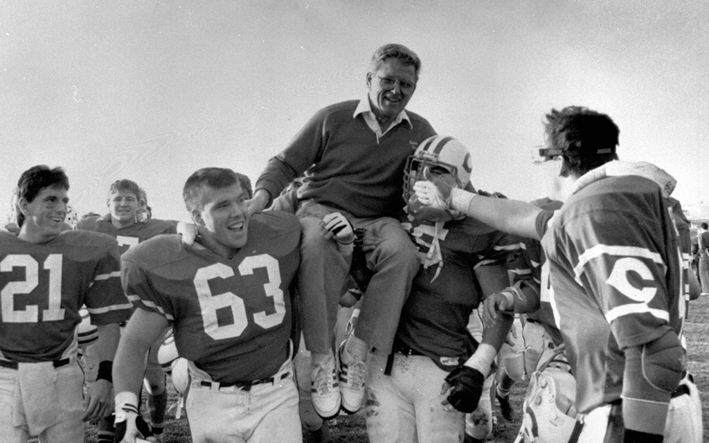 Coach Ron Schipper is carried off the field by Brad Eggers and Jon Lamb after winning the 1987 Iowa Conference title.
