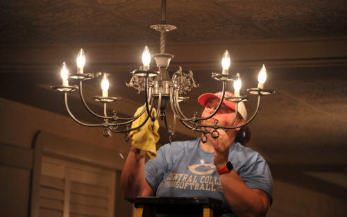 A student cleans a chandelier at Pella Opera House during Service Day in 2019.