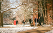 Campus with snow and five students walking outside.