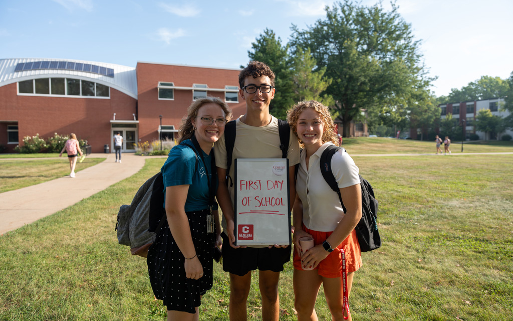Three students holding sign that reads First Day of School