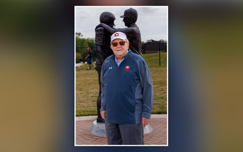 Don Lubbers standing by football statue