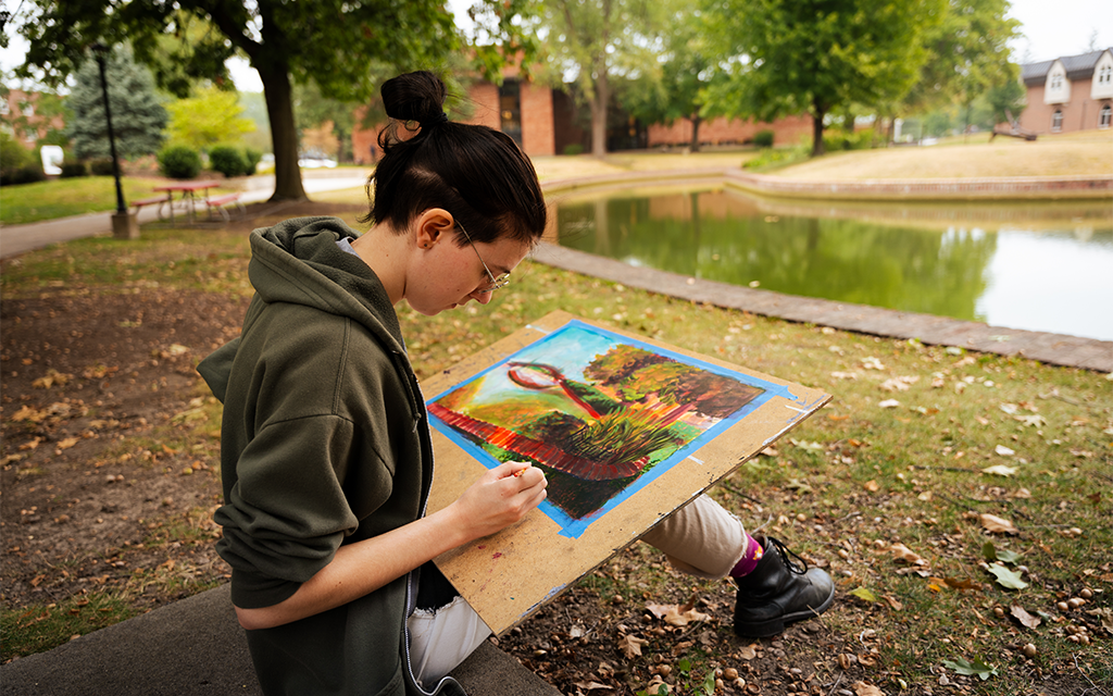 Student drawing next to pond
