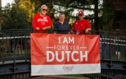 Three alumni standing on bridge with banner that reads "I Am Forever Dutch"