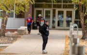 Student in a black sweatshirt skateboarding away from the Roe Center.