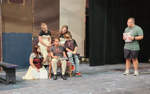 A scene from rehearsal with the Cratchit family and Mr. Scrooge.